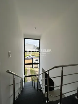 Hall de entrada com escada e corrimão em um imóvel no Brasil.