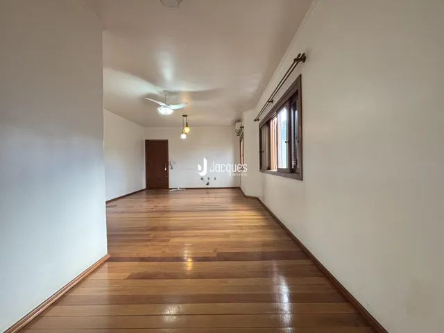 Corredor interno com piso de madeira e paredes brancas.