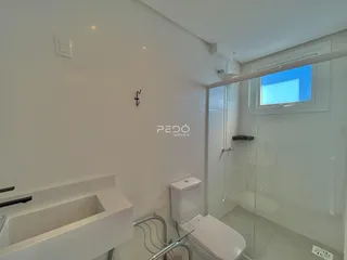 Banheiro moderno com box de vidro e louças brancas.
