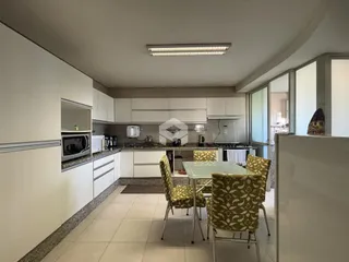 Vista interna de uma cozinha e sala de jantar moderna com armários brancos.