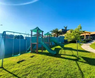 Área externa com gramado verde e playground.