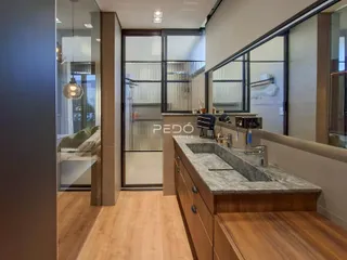 Vista da cozinha moderna com bancada de granito e piso de madeira.