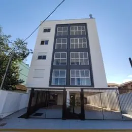 Fachada de um prédio residencial branco com janelas escuras em Lajeado, Brasil.
