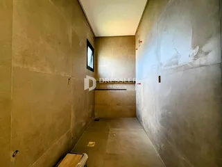 Corredor interno com paredes de cor bege e piso de concreto.