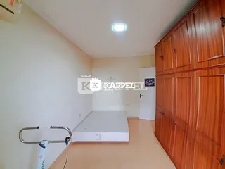 Foto interna de um quarto com cama e armário de madeira.