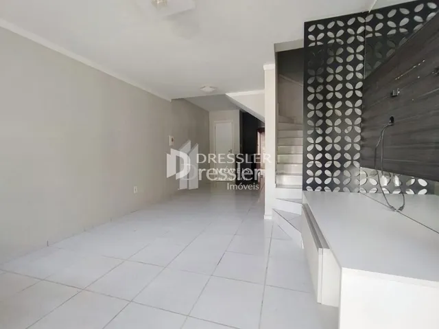 Hall de entrada com piso e paredes brancas.