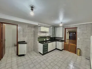 Interior de uma cozinha com revestimento cerâmico e armários brancos.