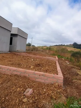 Foto de um terreno com cerca de tijolos vermelhos em área de construção.