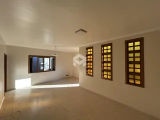 Ambiente interno amplo com piso de madeira e janelas com caixilhos de madeira.