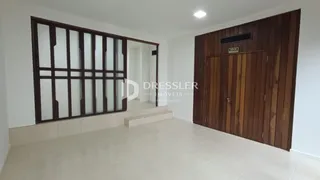 Interior de uma sala com portas de madeira e piso de cerâmica clara.
