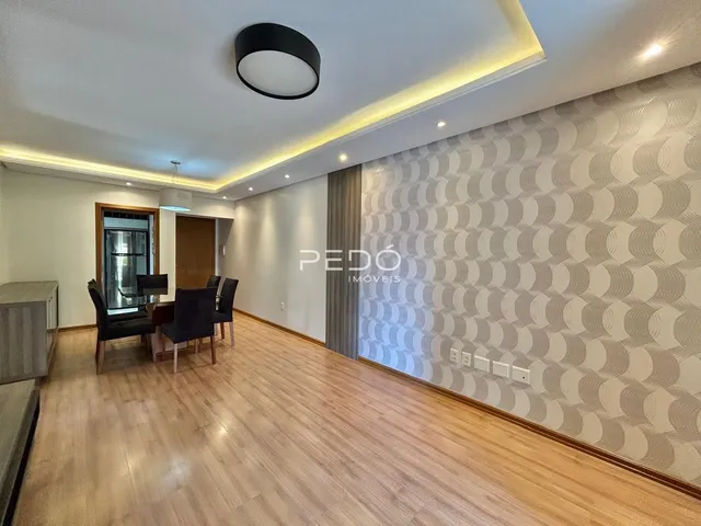 Sala de estar com piso de madeira e parede decorada em Lajeado.