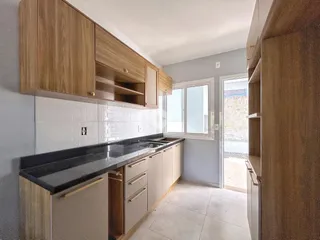 Foto de uma cozinha com armários de madeira e bancada escura.