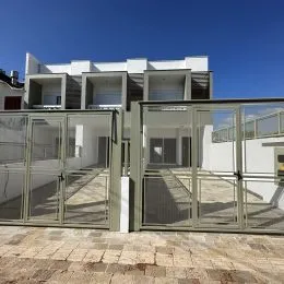 Fachada de um imóvel em Lajeado, Brasil, com portas de vidro e revestimento claro.