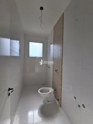 Corredor interno de uma residência com paredes brancas e piso claro.