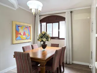 Sala de jantar com mesa de madeira e cadeiras listradas em um imóvel no Brasil.