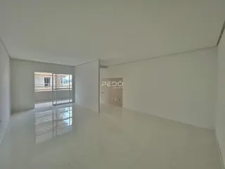 Corredor interno de um imóvel com piso claro e portas de vidro que dão acesso ao exterior.