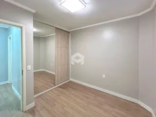 Uma sala interna com piso de madeira clara e paredes brancas.