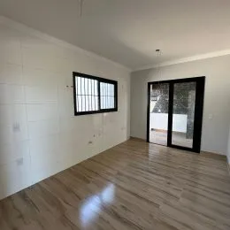 Foto de um cômodo interno com piso de madeira clara e paredes brancas.