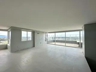 Vista ampla de um ambiente interno com grandes janelas que oferecem uma vista panorâmica.