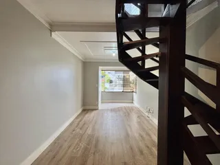 Hall de entrada com piso de madeira clara e paredes brancas.