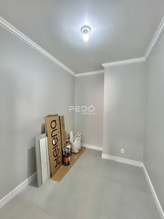 Vista interna de um corredor com paredes brancas e molduras claras.