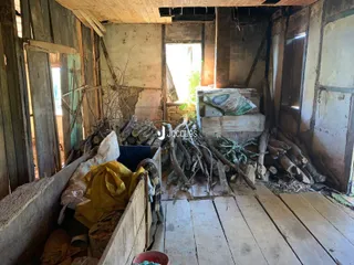 Interior de uma estrutura com paredes expostas e entulho de madeira.