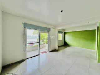 Ambiente interno de uma sala com piso de cerâmica e porta de vidro abrindo para o exterior.