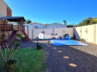 Foto externa mostrando uma piscina coberta em um terreno com gramado e área de lazer.