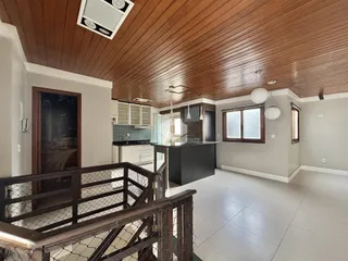 Interior de uma sala de estar com teto de madeira e cozinha moderna.