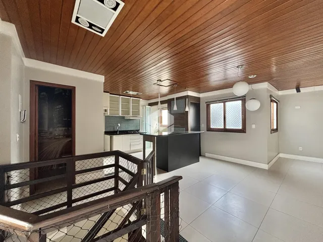 Interior de uma sala de estar com teto de madeira e cozinha moderna.