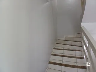 Parede branca e degraus de um corredor são visíveis na foto.