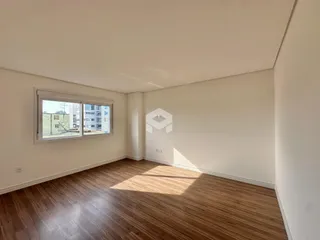 Uma sala com piso de madeira e janela de vista urbana.