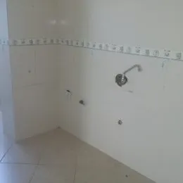 Foto interna de um ambiente com paredes brancas e piso claro.