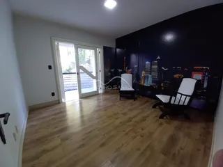 Sala de estar com piso de madeira e porta de vidro que dá acesso ao exterior.