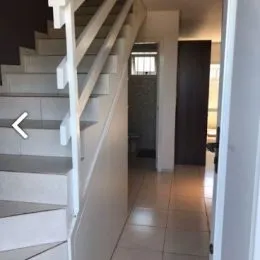 Escadaria branca com corrimão visível em um corredor interno.