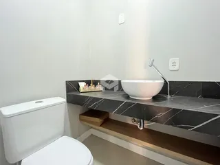 Banheiro moderno com bancada de mármore e vaso sanitário branco.