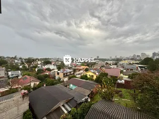 Vista aérea de um bairro residencial com telhados e vegetação sob um céu nublado.