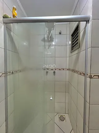 A foto mostra o interior de um banheiro com box de vidro.