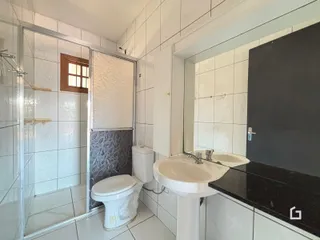 Banheiro com revestimento cerâmico e box de vidro.