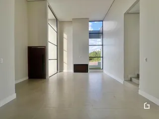 Vista de um corredor interno moderno com piso de cerâmica clara.