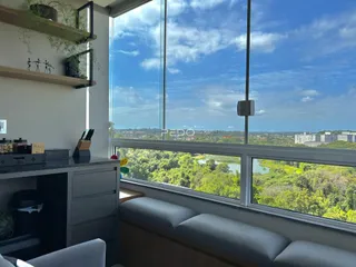 Sala de estar com grande janela oferecendo vista para a paisagem verde.