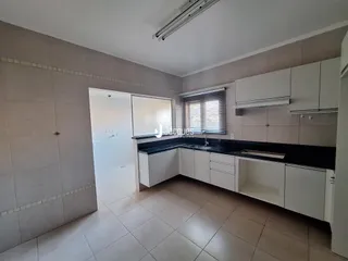 Vista da cozinha com armários brancos e bancadas escuras.