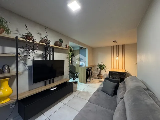 Sala de estar com sofá e televisão em um apartamento no Brasil.