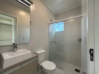 Banheiro com box de vidro e pia branca.