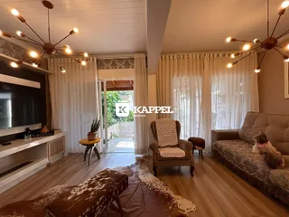 Sala de estar com piso de madeira e cortinas claras.