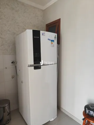 Uma geladeira branca está instalada em uma parede clara de uma residência.