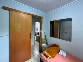 Vista de um corredor interno com porta de madeira e um quarto ao fundo.