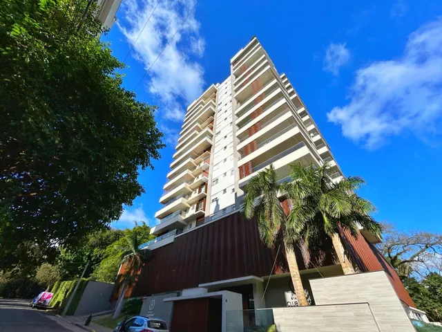 Fachada de um prédio residencial em Lajeado, Brasil, com vegetação ao redor.