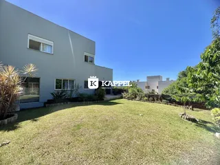 Fachada de uma casa moderna com gramado verde sob um céu azul.
