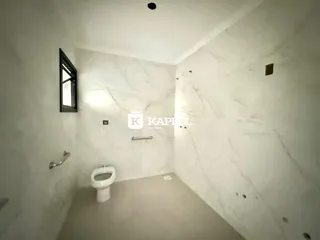 Foto de um banheiro com paredes de mármore branco e vaso sanitário.